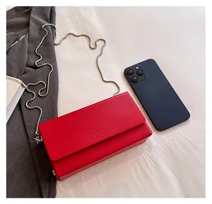 Detail shot of a red leather chain bag showing storage capacity for a smartphone