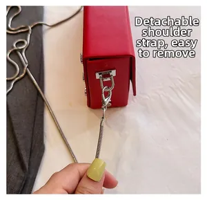 Detail of red square crossbody bag showing silver detachable chain strap with lobster clasp