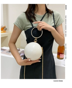 Detailed view of white spherical shell bag with sparkling rhinestone handle and gold chain