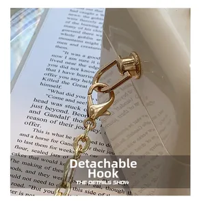 Close-up of golden detachable metal hook and chain on cream acrylic handbag