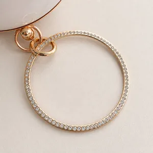 Close-up of golden circular metal handle with sparkling rhinestones on the beige bag