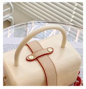 Detailed close-up of a glossy beige jelly bag with red edge paint and gold metal accents