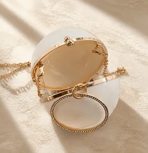 Detail view of the round evening bag opening with gold hardware and rhinestone handle