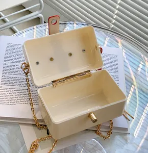Macro view of cream box bag interior with gold chain strap and metal clasp detail