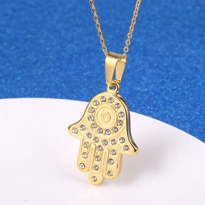 Collier pendentif Main de Fatma dorée orné de strass blancs sur un fond contrasté