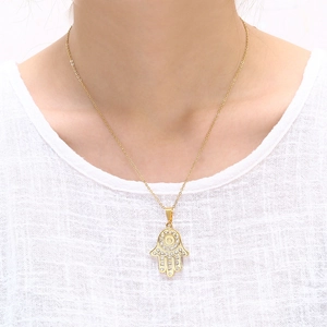 Collier main de Hamsa doré avec cristaux de zircon sur la clavicule d'une femme élégante