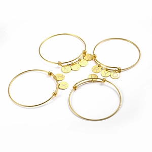 Detailed view of adjustable gold titanium bracelets with engraved round letter charms