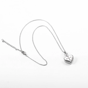 Dettaglio del ciondolo a cuore in argento con incisione a croce e diamanti laterali