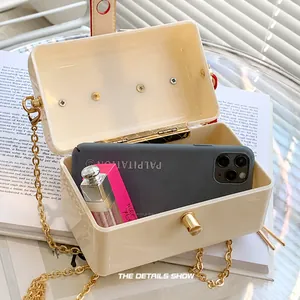 Detail view showing interior capacity of cream crossbody bag with phone and lipstick