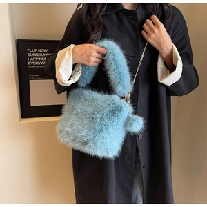 Light blue fluffy plush shoulder bag with chain strap and cute pompom charm detail.