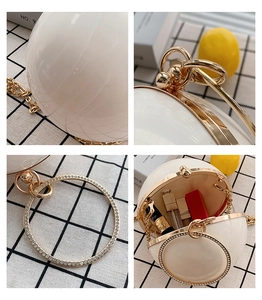 Detail of round pearl sphere clutch bag with rhinestone handle and gold metal chain