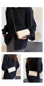Macro shot of minimalist cream leather crossbody bag with elegant metal chain strap detail