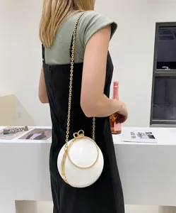 Detailed view of a white spherical evening bag with rhinestone handle and gold chain strap