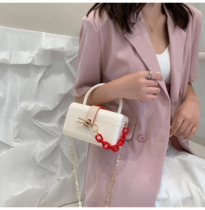 Detail of white acrylic jelly bag with red chain handle and gold shoulder strap