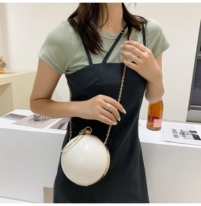 Close-up of white spherical pearl handbag with gold chain strap in a lifestyle setting