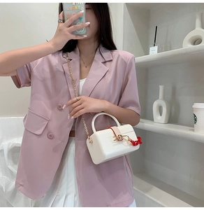 Chic white mini box bag with gold chain strap and cherry charm shown on model