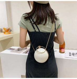Spherical pearl white hard shell crossbody bag with a golden circular handle and chain