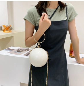 Close-up of pearl white spherical bag with diamond-encrusted gold ring handle