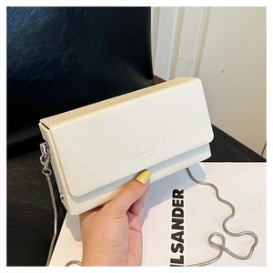 Detail of a creamy white rectangular crossbody bag with silver snake chain and logo