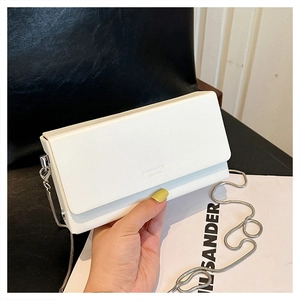 Detail of white leather chain bag featuring embossed logo and sleek silver metal strap