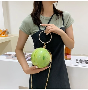 Detail of creative green marble spherical clutch with gold chain and ring handle