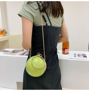 Green marble sphere clutch bag with rhinestone handle and gold chain strap in use