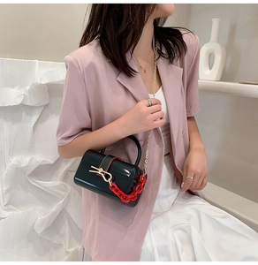 Mini black lacquer crossbody bag with gold rabbit ear clasp and chunky red chain strap