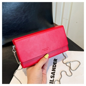 Macro detail of red leather mini bag with silver chain strap and embossed front logo