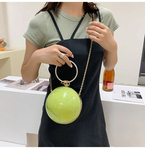Detail of round marble texture evening bag with golden handle and chain strap