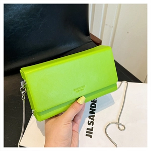 Close-up of textured lime green leather crossbody bag with silver snake chain strap