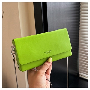 Detail of bright green crossbody bag featuring silver chain strap and embossed logo