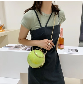 Detail of a spherical marble-pattern clutch bag with gold ring handle and chain strap