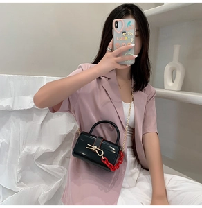 Black acrylic jelly bag with gold bow clasp and red chain detail on pink blazer