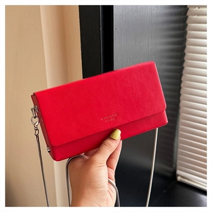 Detail view of red square crossbody bag featuring matte leather texture and silver chain strap