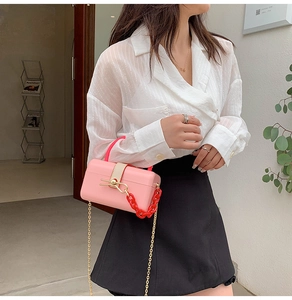 Detailed shot of pink acrylic jelly bag with red chain and gold metal strap detail