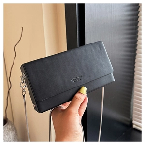 Detail view of the black flap bag showing silver chain strap and brand logo engraving