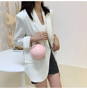 Detail of pink spherical wristlet bag with pearl luster and delicate gold chain strap