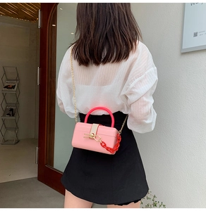 Rear view of a pink acrylic mini trunk bag with red chain and gold shoulder strap