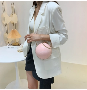 Chic pink spherical hard shell evening bag with a gold round handle and chain strap