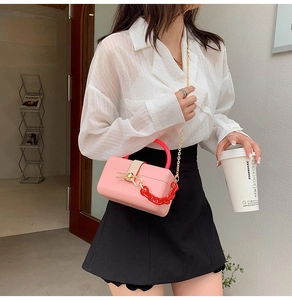 Pink structured mini handbag with bold red acrylic chain and gold shoulder strap detail