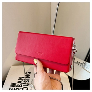 Close-up of red minimalist crossbody bag with silver snake chain and brand engraving