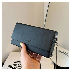 Close-up of minimalist black square bag with silver chain and fine leather texture