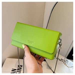 Detail of neon green leather square bag with silver chain strap and embossed brand logo