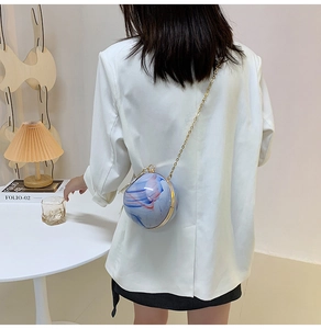 Detail of blue and white marble spherical crossbody bag with gold chain on model