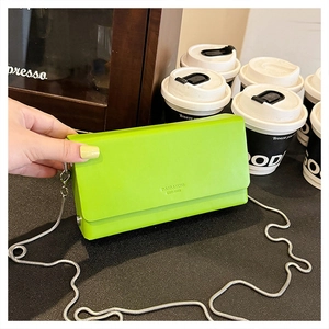 Detail view of a bright green rectangular crossbody bag with silver snake chain and logo
