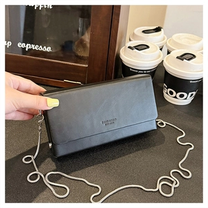 Detail shot of black faux leather rectangular bag with silver chain and magnetic closure