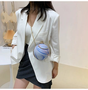 Detail of blue and white marble pattern sphere bag with golden chain and ring handle