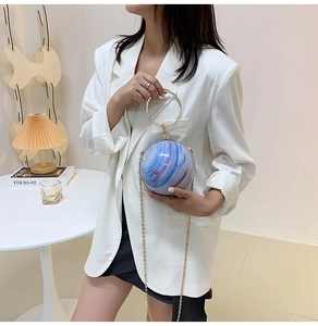 Macro view of blue, white, and red marble texture on round sphere evening bag with gold ring