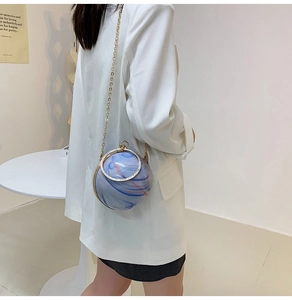 Detail of a spherical marble-pattern evening bag with gold chain and rhinestone ring handle