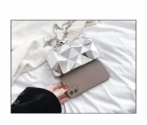 Silver geometric evening clutch with chain strap shown next to a phone for size reference